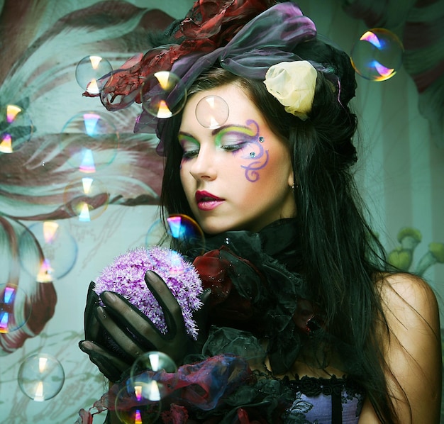 Fashion model with creative makeup blowing soap bubbles