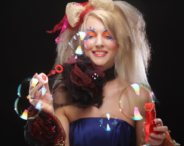 Photo fashion model with creative makeup blowing soap bubbles