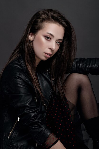 Fashion model woman in a black jacket on a gray background