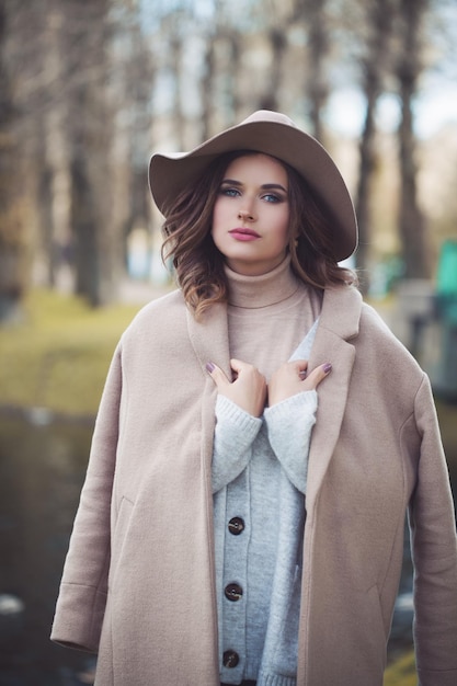 Fashion model woman in season cot and fashionable hat outdoor