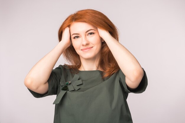 Fashion, modeling and people concept -young woman hide ran her hands in red head and smile.