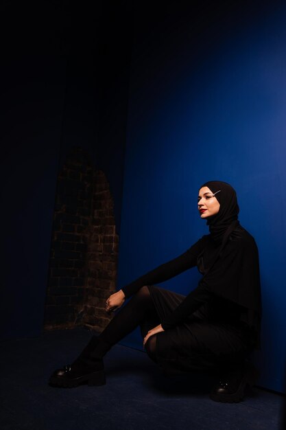 Fashion muslim model in black hijab is posing on blue background in studio Islam religion creative photo