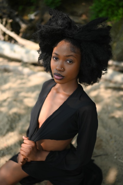 Foto ritratto di spiaggia all'aperto di moda una bella giovane donna nera afroamericana che posa fuori sulla sabbia