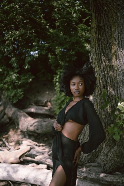 Foto ritratto di spiaggia all'aperto di moda bellissima giovane donna nera afroamericana che posa fuori sulla sabbia