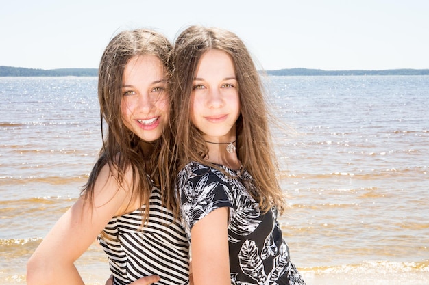 Fashion outdoor photo of two beautiful young girls Beauty portrait of twins sisters
