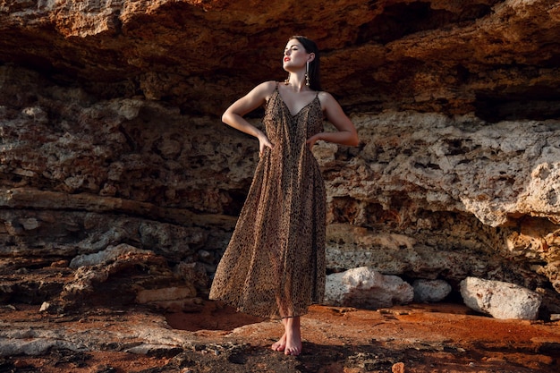 Photo fashion outdoor portrait of sexy beautiful elegant woman with long hair dressed in a luxurious evening dress posing on the summer beach