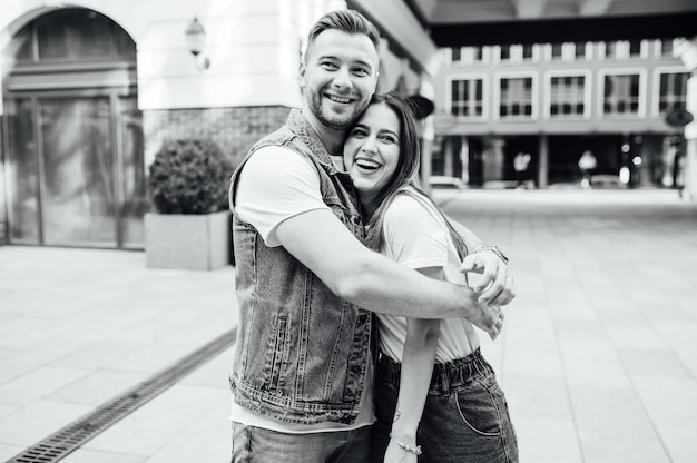 Fashion outdoor romantic portrait of beautiful young couple in love and hugs on the street.