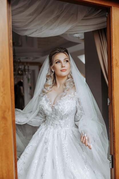 화려한 웨딩 드레스와 화려한 메이크업으로 화려한 머리카락을 가진 아름다운 신부의 패션 사진 결혼식의 아침에 방에서 신부는 결혼식을 준비하고 있습니다.