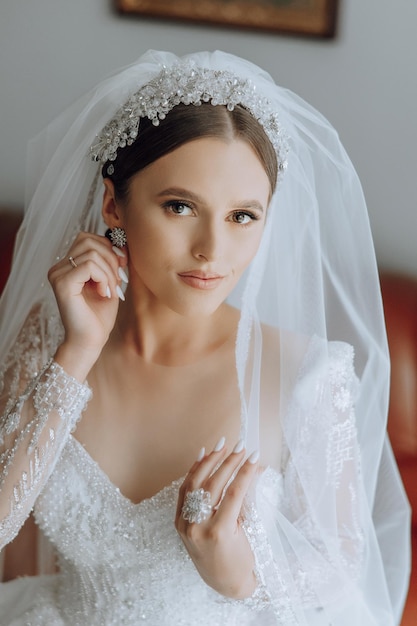 fashion photo of a beautiful bride with dark hair in an elegant wedding dress and stunning makeup in the room on the morning of the wedding The bride is preparing for the wedding