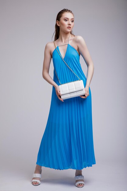 Fashion photo of beautiful elegant woman in a pretty rich blue long dress handbag clutch