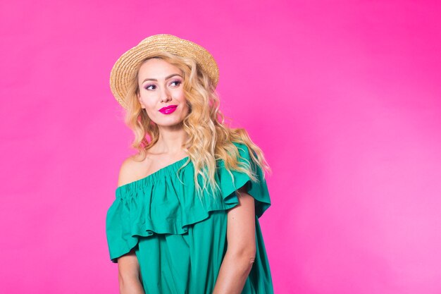 Fashion photo of a beautiful elegant young woman in a pretty dress posing over pink background