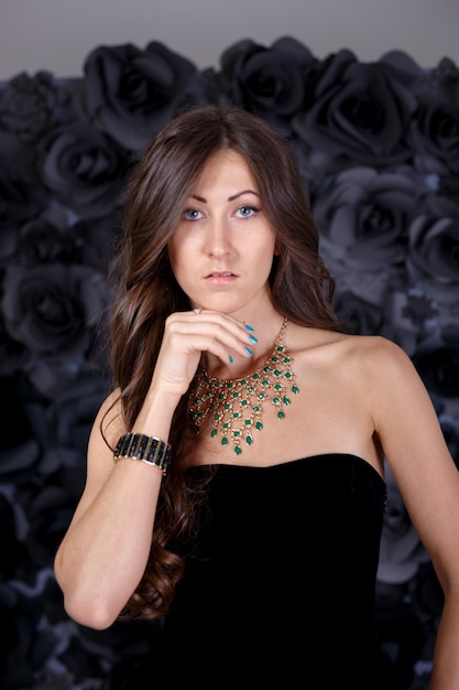 Fashion photo of beautiful young woman with dark hair wears elegant black dress,posing in studio