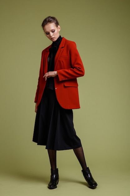 緑の背景にスーツの赤いジャケットブラウスショートパンツの女性のファッション写真スタジオショット