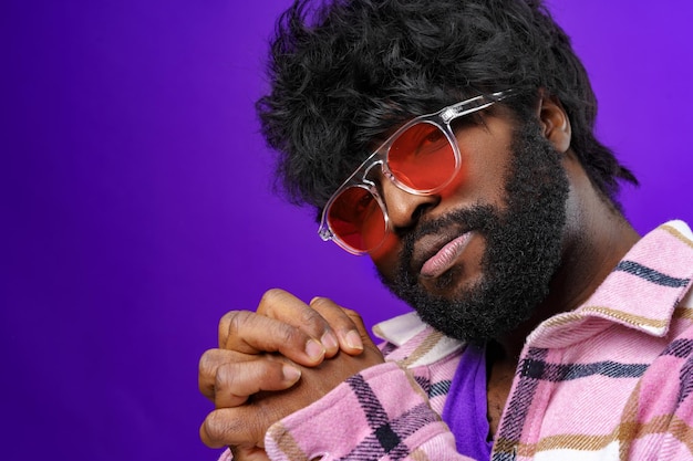 Foto ritratto di moda di un uomo afroamericano con occhiali su sfondo viola