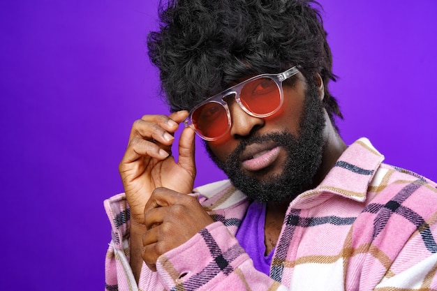 Fashion portrait of african american man in glasses against purple surface