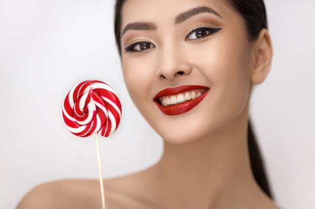 Fashion Portrait of Asian Woman with Lollipop in Studio