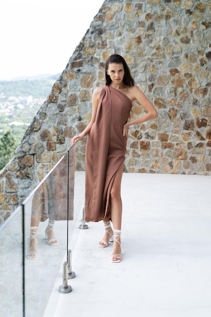 Fashion portrait of beautiful brunette woman posing in stylish evening dress outdoor natural daylight