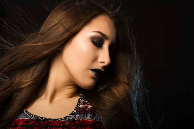 Fashion portrait of beautiful tanned woman with flying hair and art makeup, space for text