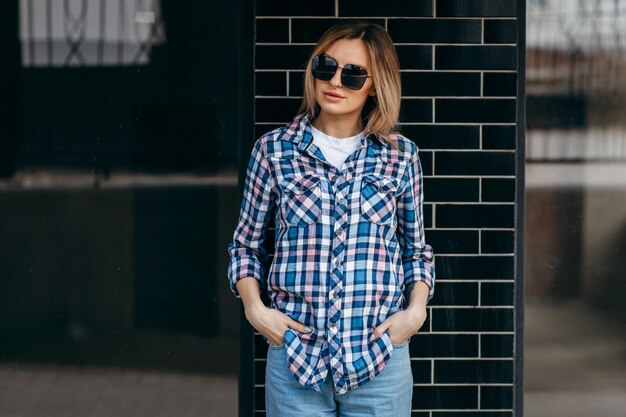 Moda ritratto di bella donna con bel viso che indossa la camicia a quadri grunge in posa da solo