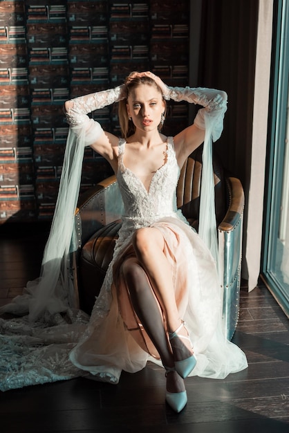 Moda ritratto di sposa con un abito lungo vicino alla finestra in attesa dello sposo interiore di nozze