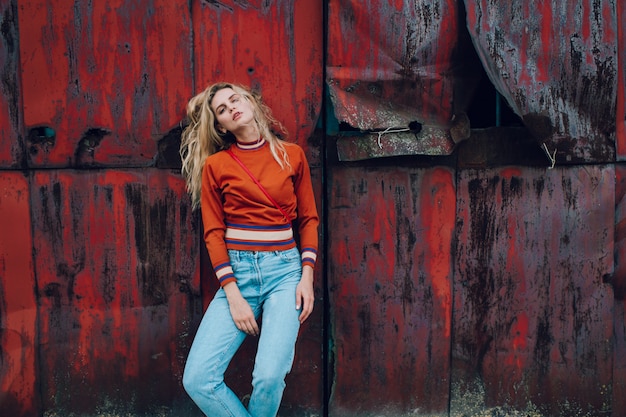 Photo fashion portrait of cute blonde girl posing over rusty metallic wall