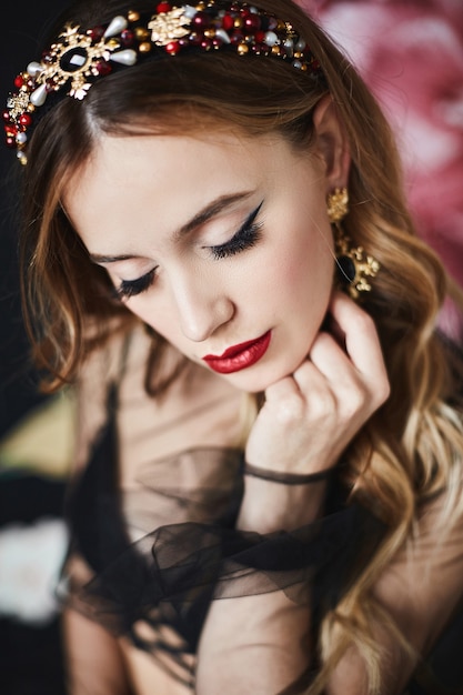 Fashion portrait of elegant luxurious woman with perfect makeup and expensive trendy gold jewelry. Model girl with wavy hairstyle, bright makeup and sexy red lips. Luxury life. Luxurious fashion