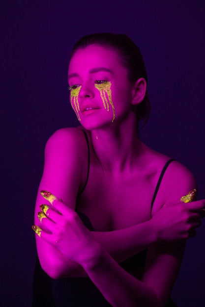 Fashion portrait A girl with fluorescent paint on her body poses under neon light