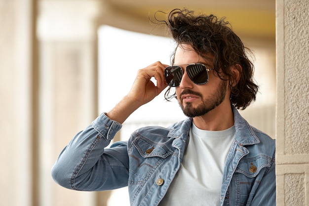 Fashion portrait of handsome elegant man with curly hair wearing sunglasses outdoor