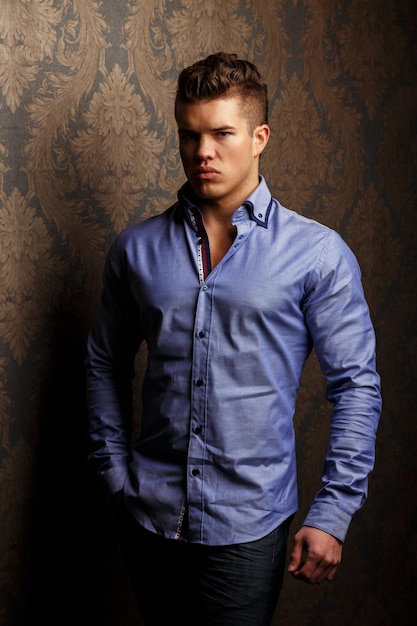 Fashion portrait of man in shirt poses over wall