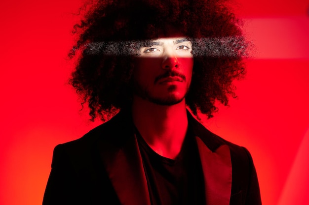 Fashion portrait of a man with curly hair on a red background multinational colored light trendy modern concept