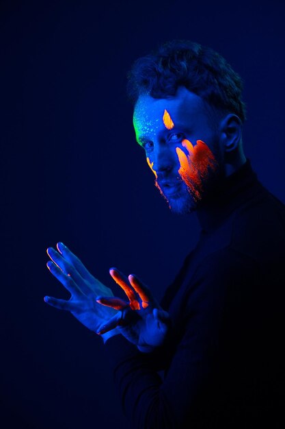 Fashion portrait A man with fluorescent paint on his face under neon light