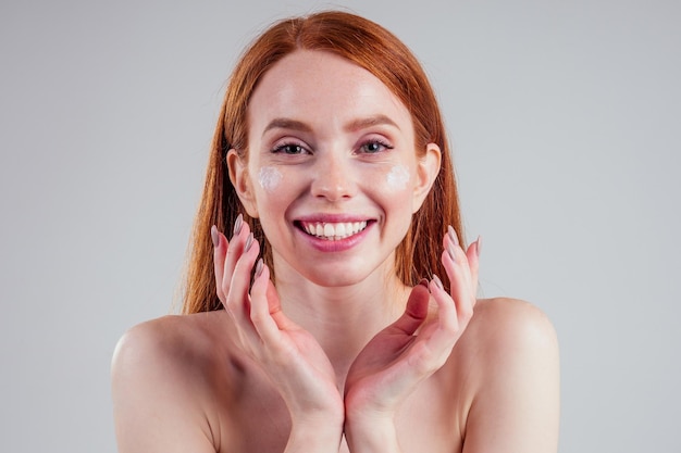 Fashion portrait of redhead model nude with perfect skin studio on white background