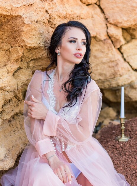 Fashion Portrait of sexy brunette woman in boudoir lace dress with jewelry. Bride's morning. Fine art wedding. Beautiful lady with wedding hairstyle long curly hair and bridal makeup.