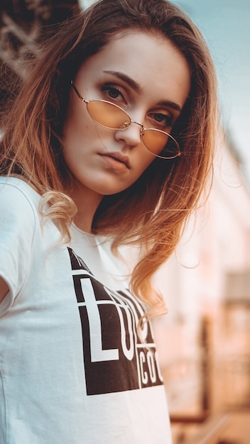 Fashion portrait stylish pretty woman in sunglasses posing in the city street fashion Sunny light