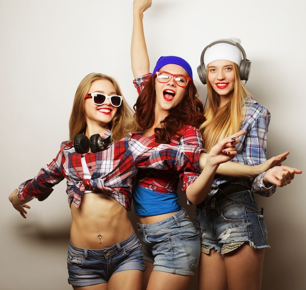 Photo fashion portrait of three stylish sexy hipster girls best friends, over gray surface