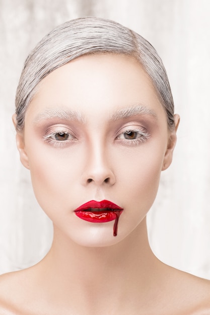 Photo fashion portrait of a vampire girl with blood. contact lenses