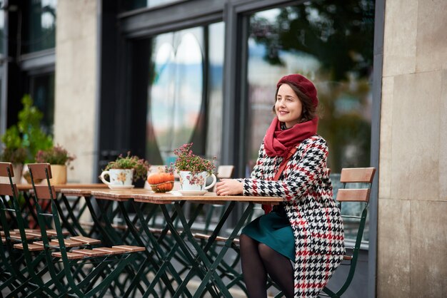 Fashion portrait of woman sitting in street cafe of Budapest