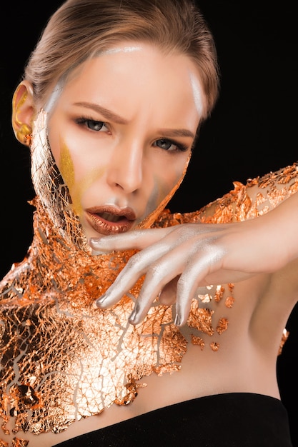 Fashion portrait of wonderful blonde woman with copper foil on her face, neck and shoulders