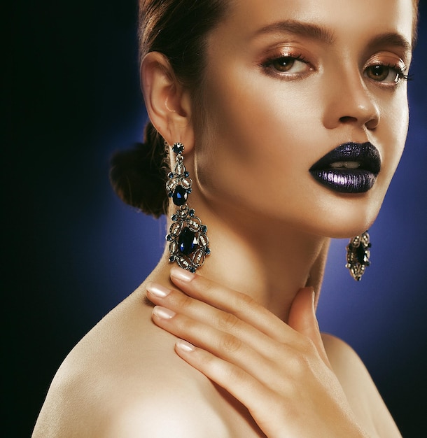 Fashion portrait of young beautiful woman with jewelry Perfect makeup Blue lips