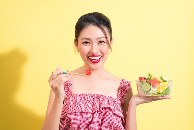 サラダのボウルでポーズをとって夏の衣装で若いファッショナブルな女性のファッションの肖像画