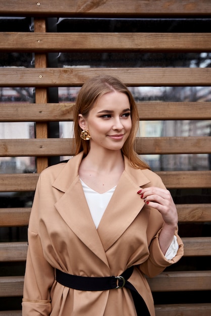 Fashion Portrait Young woman posing outdoors. Lady in a stylish summer outfit. woman posing in a brown coat. Stylish Hairstyle.