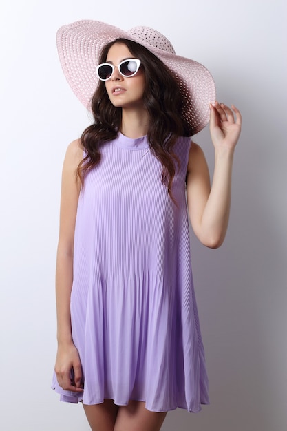 Fashion portrait of young woman wearing hat and sunglasses.