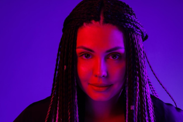 Fashion portrait of young woman with dreadlocks in neon light