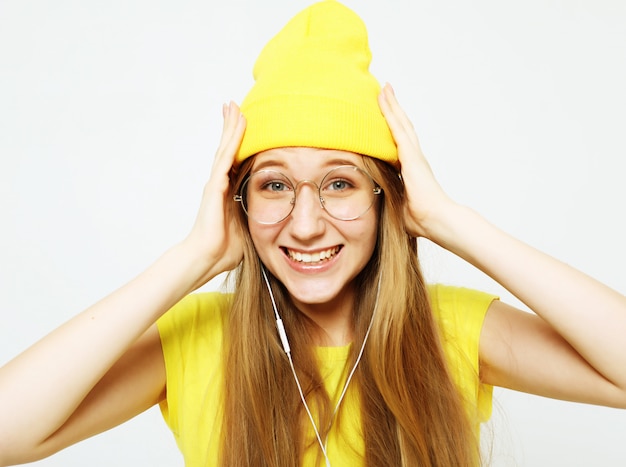 Photo fashion pretty cool girl in headphones listening to music wearing yellow hat  and t-shirt over white background