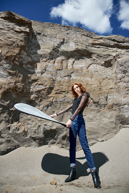 Fashion red-haired woman posing in nature near sandy rocks