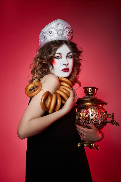 Модная русская женщина в кокошнике с самоваром на красном фоне, яркий макияж