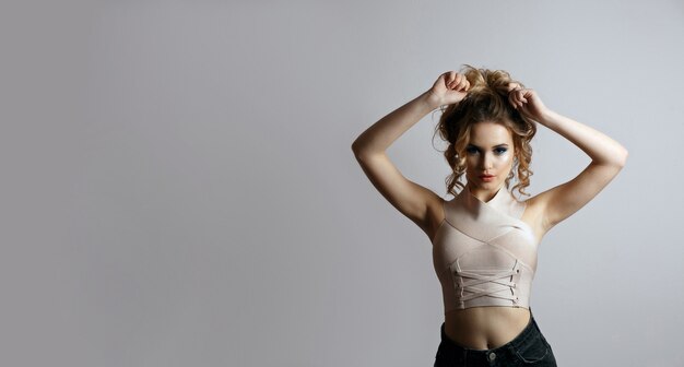 Fashion shot of stunning young woman with bright makeup wears bandage silver top. Empty space