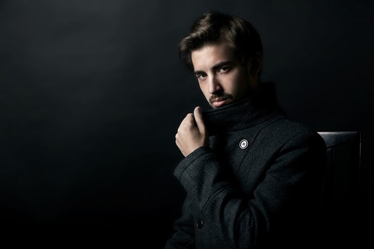 Photo fashion shot of a young handsome man in coat on black background