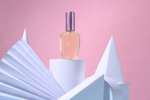 ピンクのパステルカラーの背景に香水瓶と幾何学的な形のファッションショーケースコンセプトアート美容製品
