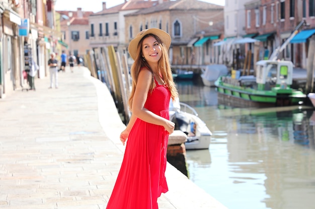 Photo fashion. smiling young stylish woman looking back walking in the old town of murano in venice, italy.